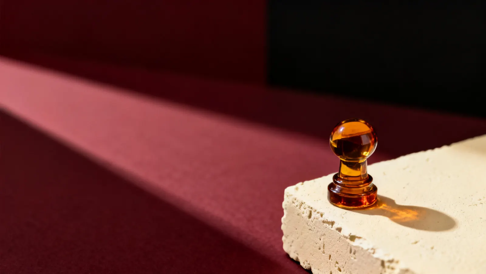 Natureza-morta em luz lateral dura: uma tampa pesada de vidro transparente, sobre fundo vinho e creme